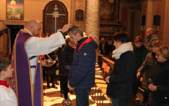 Don Massimiliano Maragno impone le ceneri sul capo ai fedeli a Mergozzo